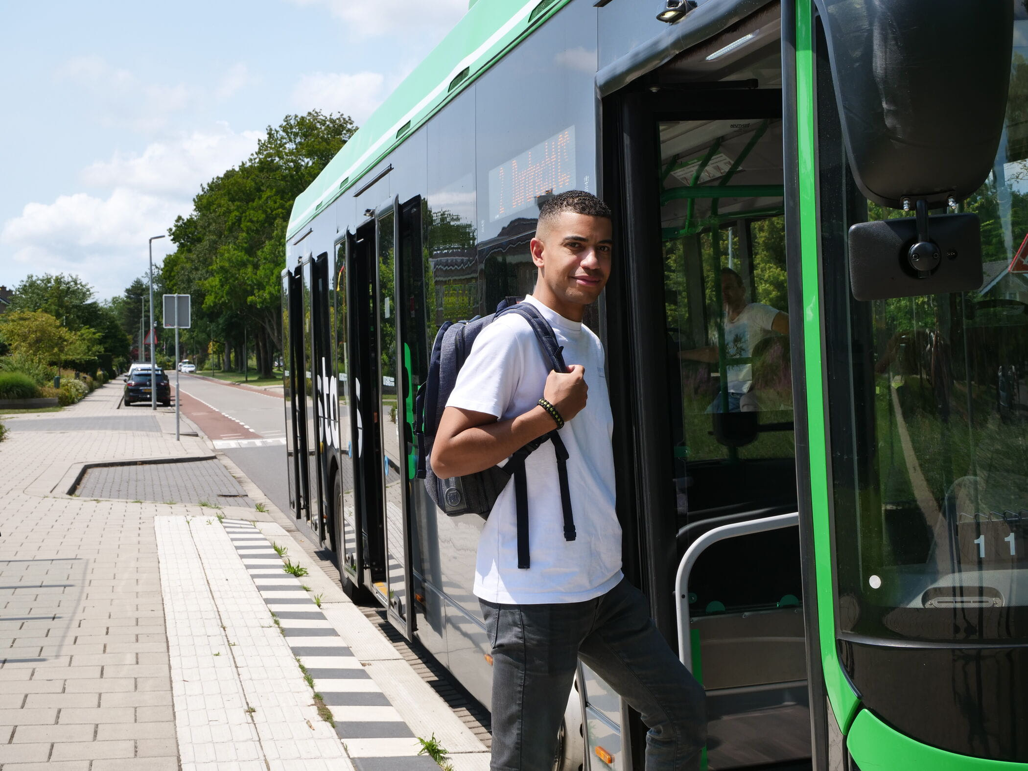 Reiziger stapt in de bus en kijkt naar de camera