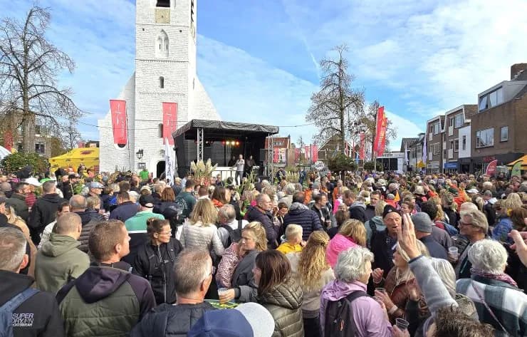 Feest op plein, publiek en een podium voor een kerktoren